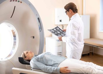 Radiology technologist looking at brain CT scan image while young woman waiting stock photo